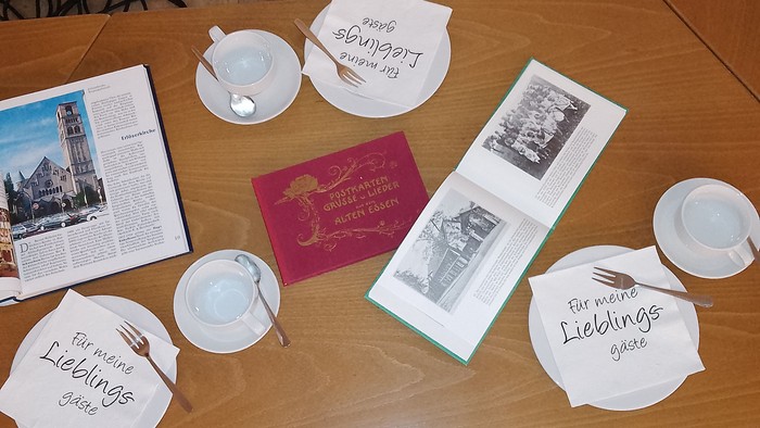 Eine gemütliche Tischdeko mit Teetassen, handgeschriebenen Notizen mit „für meinen liebsten Gast“ und Vintage-Fotos.