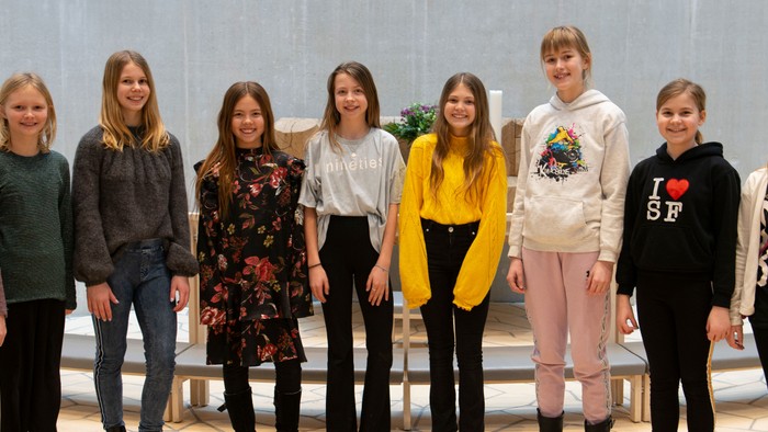 En gruppe af unge piger står sammen i en hal.