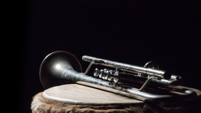 Ein silbernes Blechblasinstrument liegt auf einem Fell.