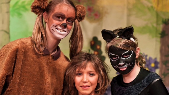 Ein Erwachsener und zwei Kinder in Tierkostümen posieren für ein Foto