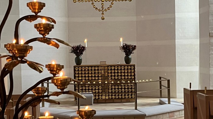 Indre del af kirke med lysende lys og blomsterdekor.