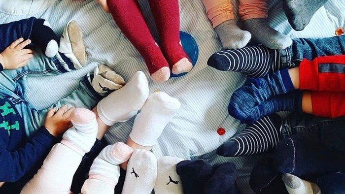 Viele Füße in Socken und Schuhen, einige mit Zehen nach oben, auf einem Teppich.