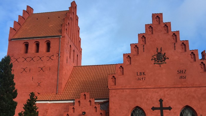 Røde kirke med tårn og gravsteder foran