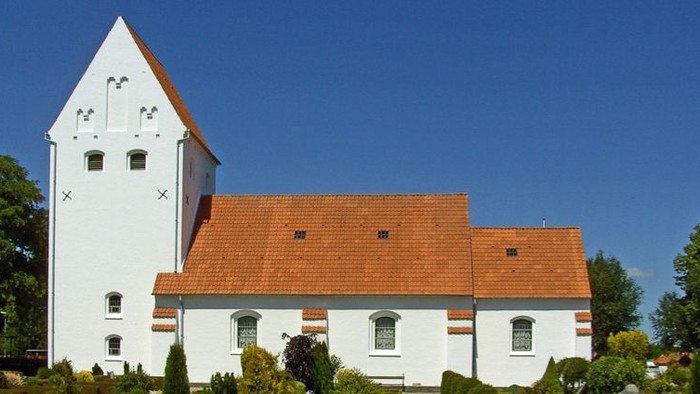 Et hvidt klokketårn med røde tag og omgivelser