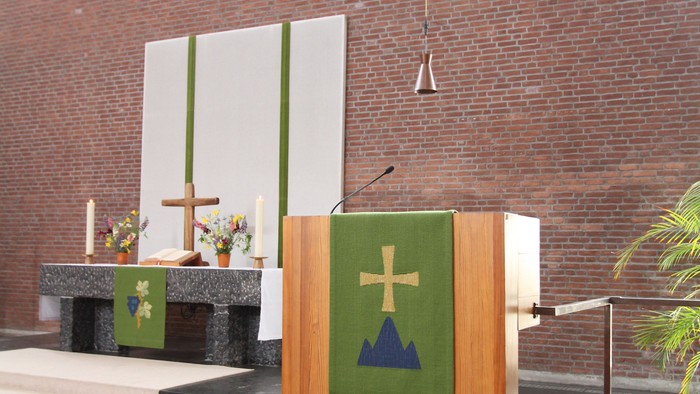 Holzpult mit Kreuzsymbol vor Ziegelmauer