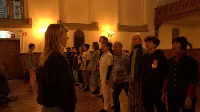 Eine Gruppe von Menschen steht in einem Raum mit hohen Decken und Kerzenlicht.