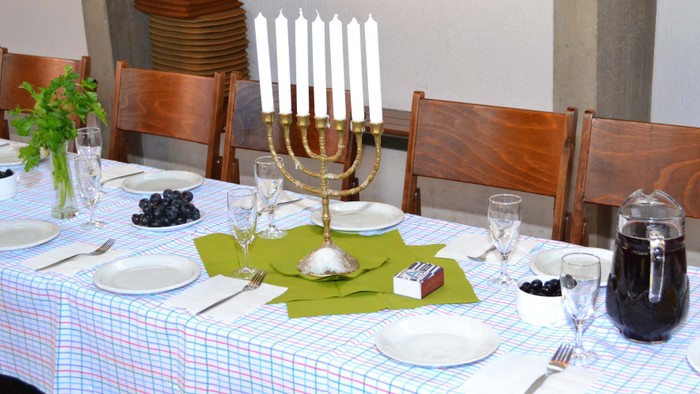 Ein festlich gedeckter Tisch mit Menora, Tellern, Besteck und Kerzen