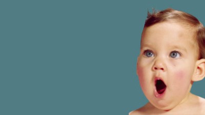 Overrasket baby med vidt åben mund på en ensfarvet blå baggrund.