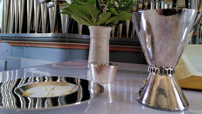 Silberne Tablett mit Besteck, Blumen in Glas und silberner Behälter