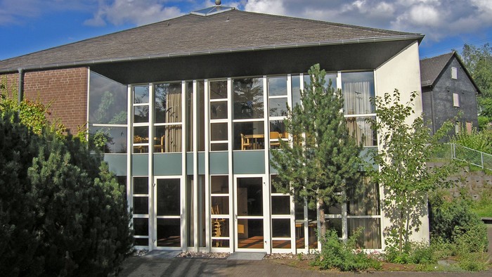 Moderne Kirche mit großem Glasfenster und Kreuz auf dem Dach unter blauem Himmel