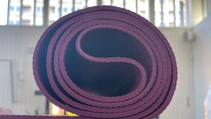 Rollede yoga-mat i mørke rød og blå farver.