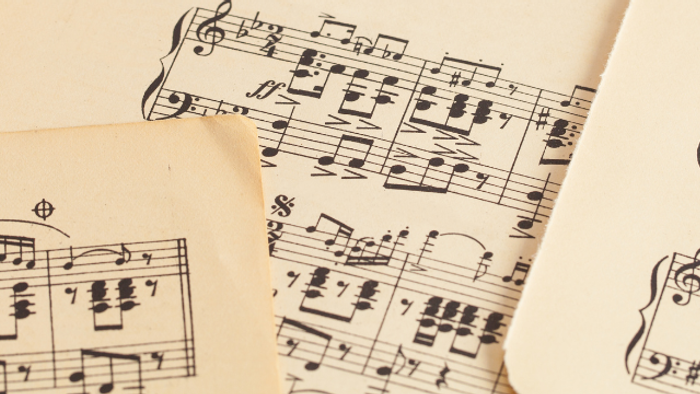 Notenblätter verstreut auf einer Oberfläche, mit verschiedenen Musiknoten und Notenlinien.