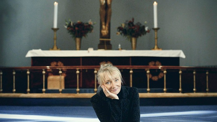 Kvinde sitter i kirke foran alter med kors.