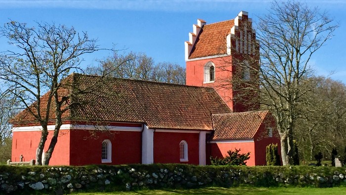 Rødt kirke med tårn og tagtegn i træ.