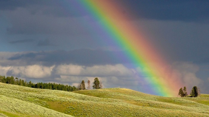 Das Bild zeigt einen Teil von einem Regenbogen über eine Hügellandschaft.