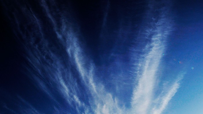 En klar blå himmel med svaleformede skyer.