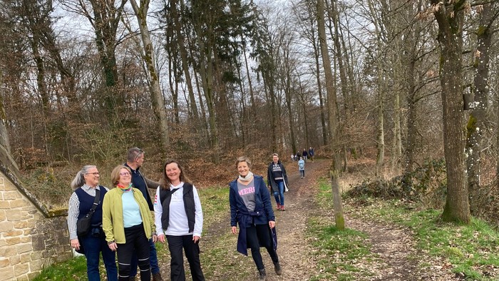 En gruppe mennesker, der går sammen ad en grussti gennem et skovklædt område.