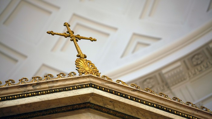 Udsmykket gyldent kors på et indviklet dekoreret kirkeloft.