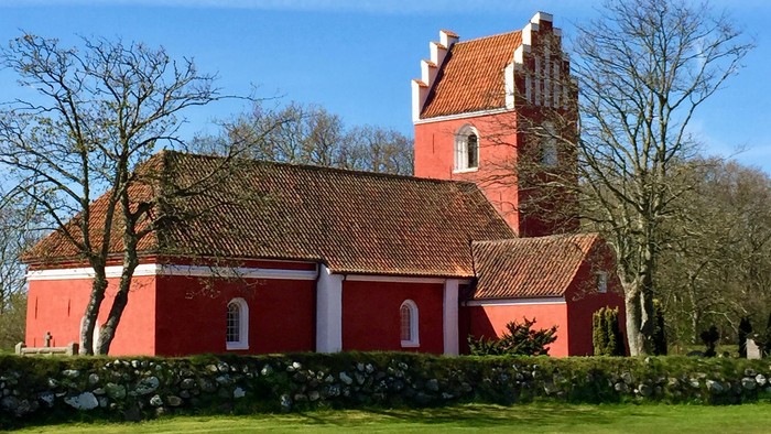 Rødt kirke med tårn og tagtegn i træ.