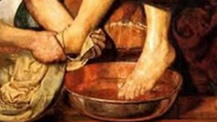 Hands holding feet over a bowl, possibly for washing.