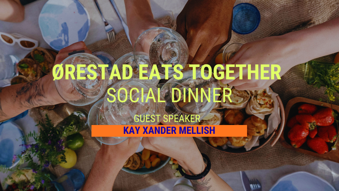 Et fugleperspektiv af en social middagsbegivenhed med mennesker, der skåler og deler mad, med gæstetaler Kay Xander Mellish.