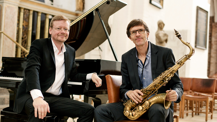 To men sitter ved piano og saxofon i klassisk miljø