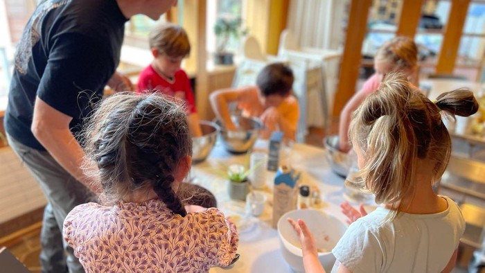 En gruppe børn og voksne sidder om bordet og spiser.