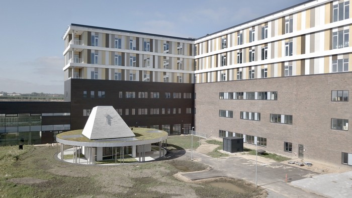 Det er et moderne boligkompleks med flere bygninger og en central plads.