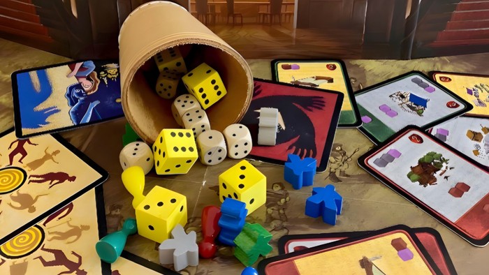 Bunte Würfel und Spielsteine auf einem Tisch mit verschiedenen Spielkarten