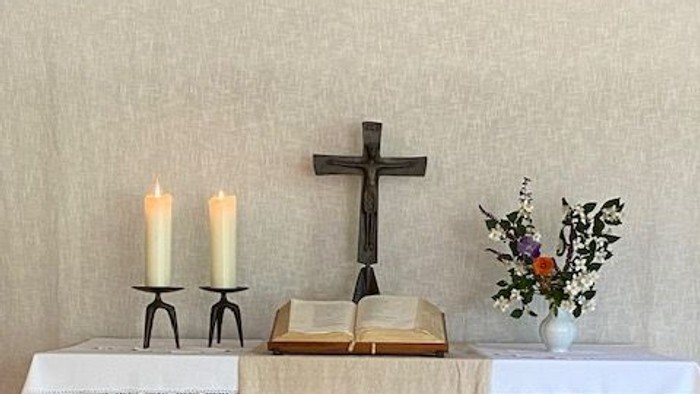 Ein Altar mit Kreuz, Kerzen und Blumen in einem Raum