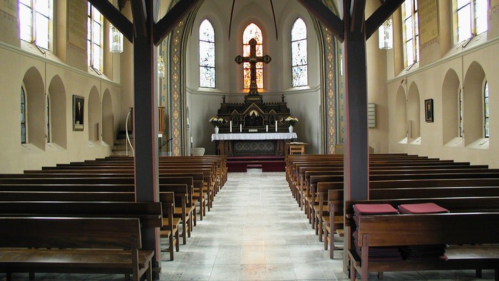 Leere Kirche mit Holzbänken und Altarraum