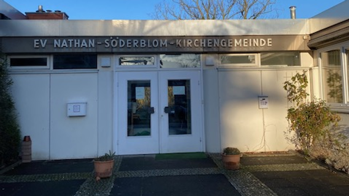 Das Gebäude der EV Nathan-Söderblom-Kirchengemeinde mit Eingangstür und Topfblumen.