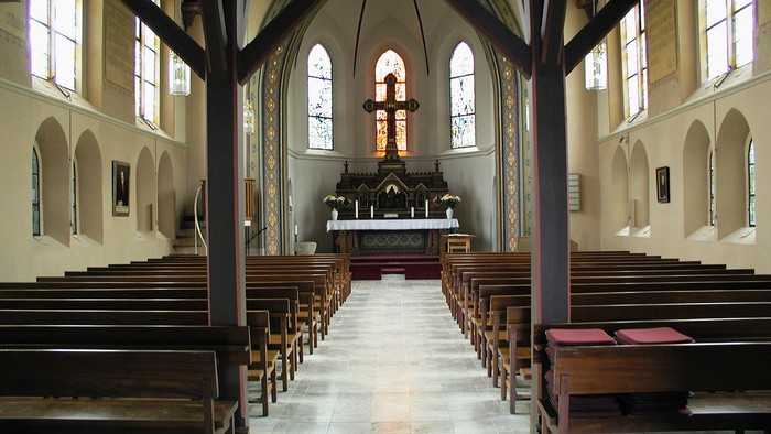 Leere Kirche mit Holzbänken und Altarraum