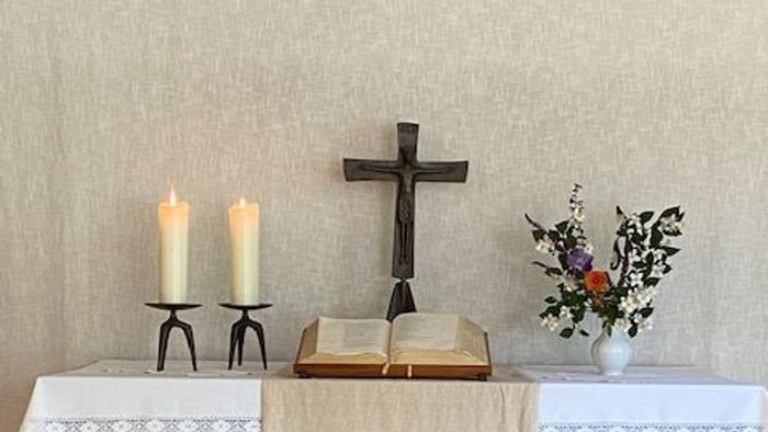 Ein Altar mit Kreuz, Kerzen und Blumen in einem Raum