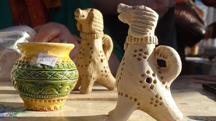 Handgefertigte Keramik-Hundefiguren und eine dekorative Vase auf einem Tisch ausgestellt.