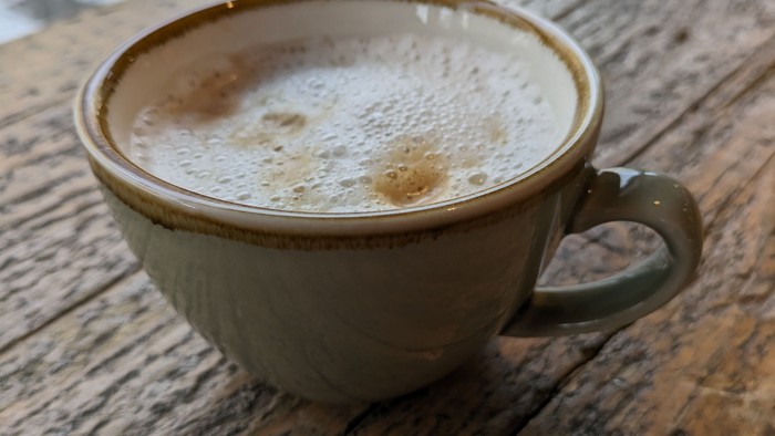 Eine Tasse Cappuccino auf einem Holztisch.