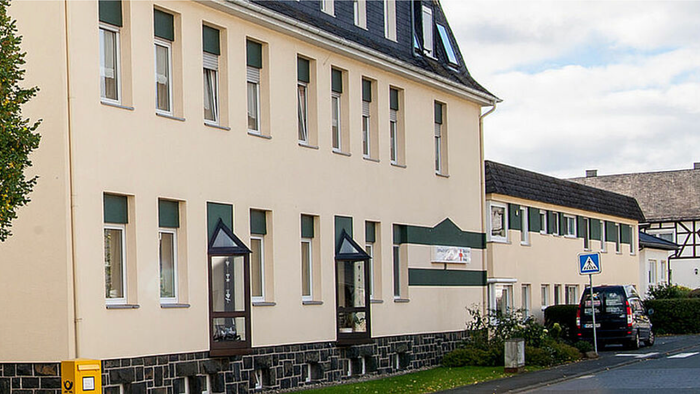 Gelbe Hauswand mit grünen Fensterläden und Auto davor