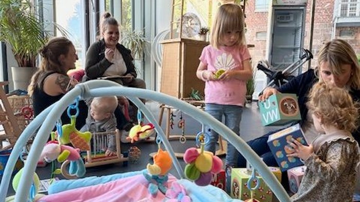 Kinder spielen in einem Zimmer mit einer Katze auf einer Decke.