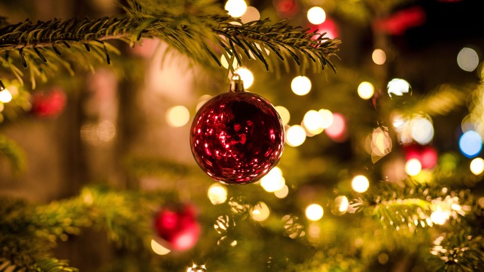 En glitrende rød pyntestjerne hænger på en juletree med lys.