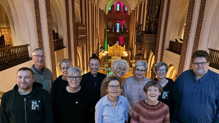 Gruppe af mennesker, der poser i en prægtig kirkeinteriør.