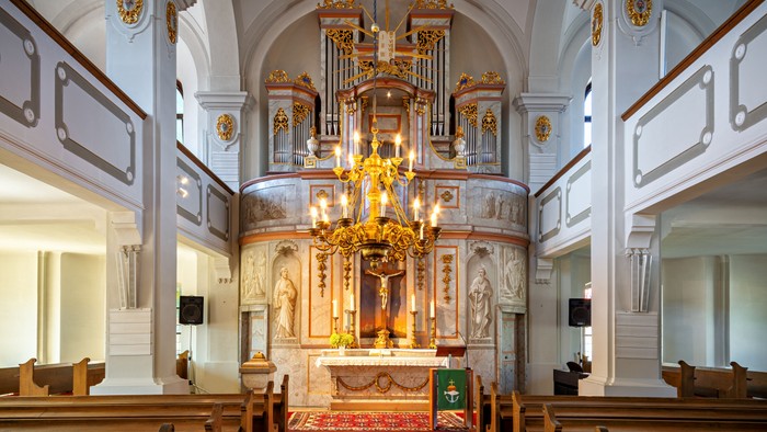 Kircheninneres mit Kronleuchter, Altar und Kirchenbänken