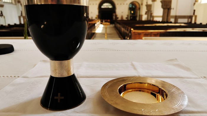 Ein schwarzer Kelch und eine goldene Patene auf einem Tisch in einer Kirche