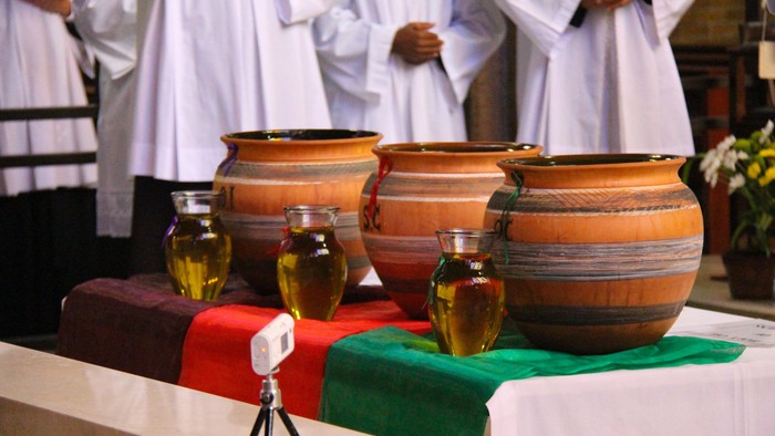 Drei große Tonkrüge mit kleinen Ölflaschen auf Tisch