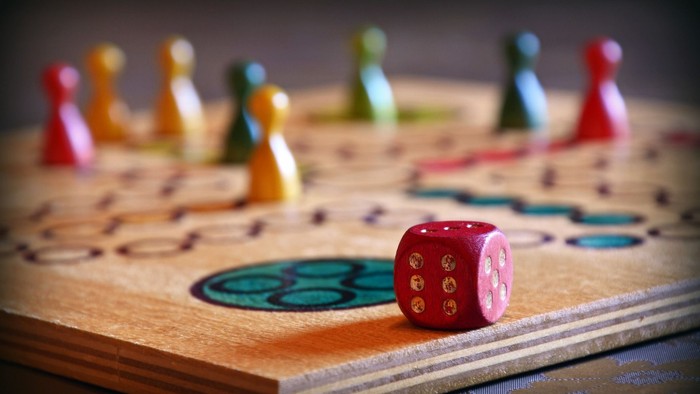 Hölzernes Brettspiel mit bunten Spielfiguren und Würfeln.