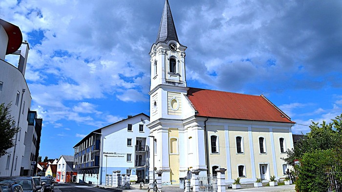 Kirchengemeinde mit weißem Turm und rotem Dach in kleiner Stadt