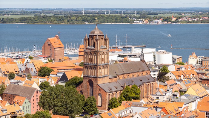 Die Stadt mit einem hohen Kirchturm und einem Hafen im Hintergrund