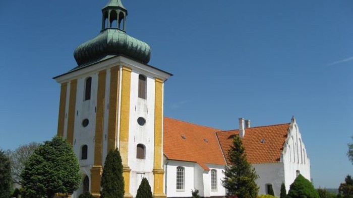 Et hvide kloster med gul og hvid fasade og en grøn kuppel.
