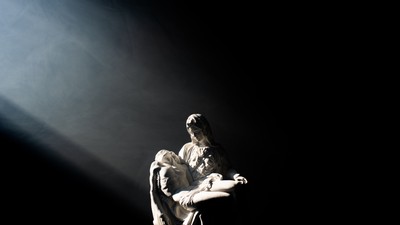 A person holding a child, illuminated by a spotlight.