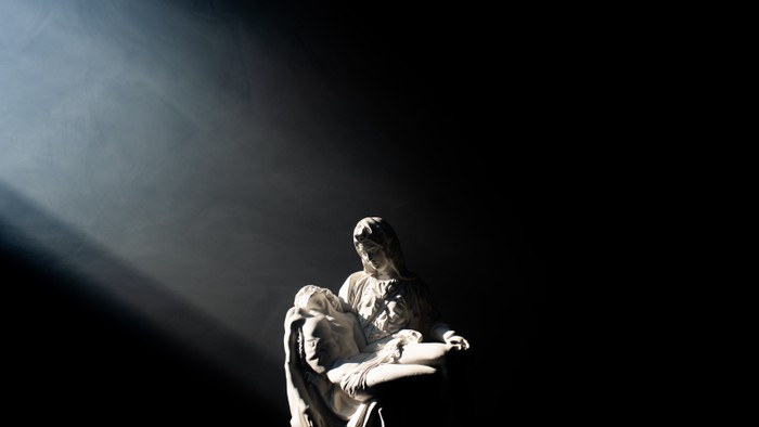 A person holding a child, illuminated by a spotlight.