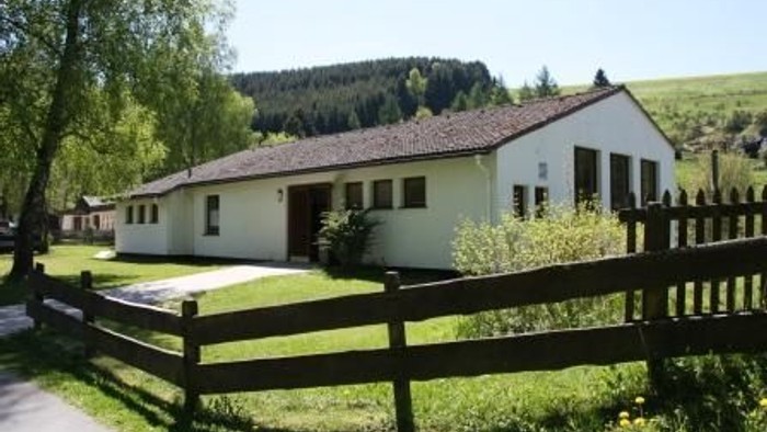 Ein weißes Haus mit braunem Dach und Holzzaun im Vordergrund.